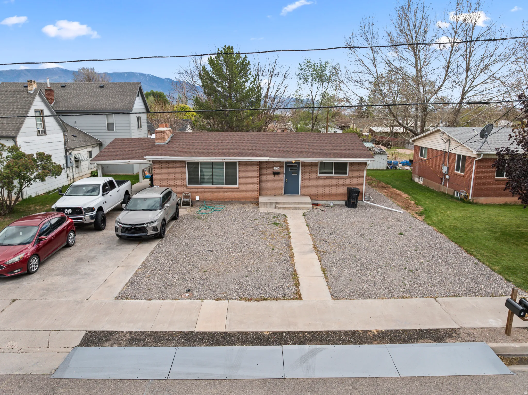 Brick exterior home featuring a concrete driveway and an additional gravel parking area