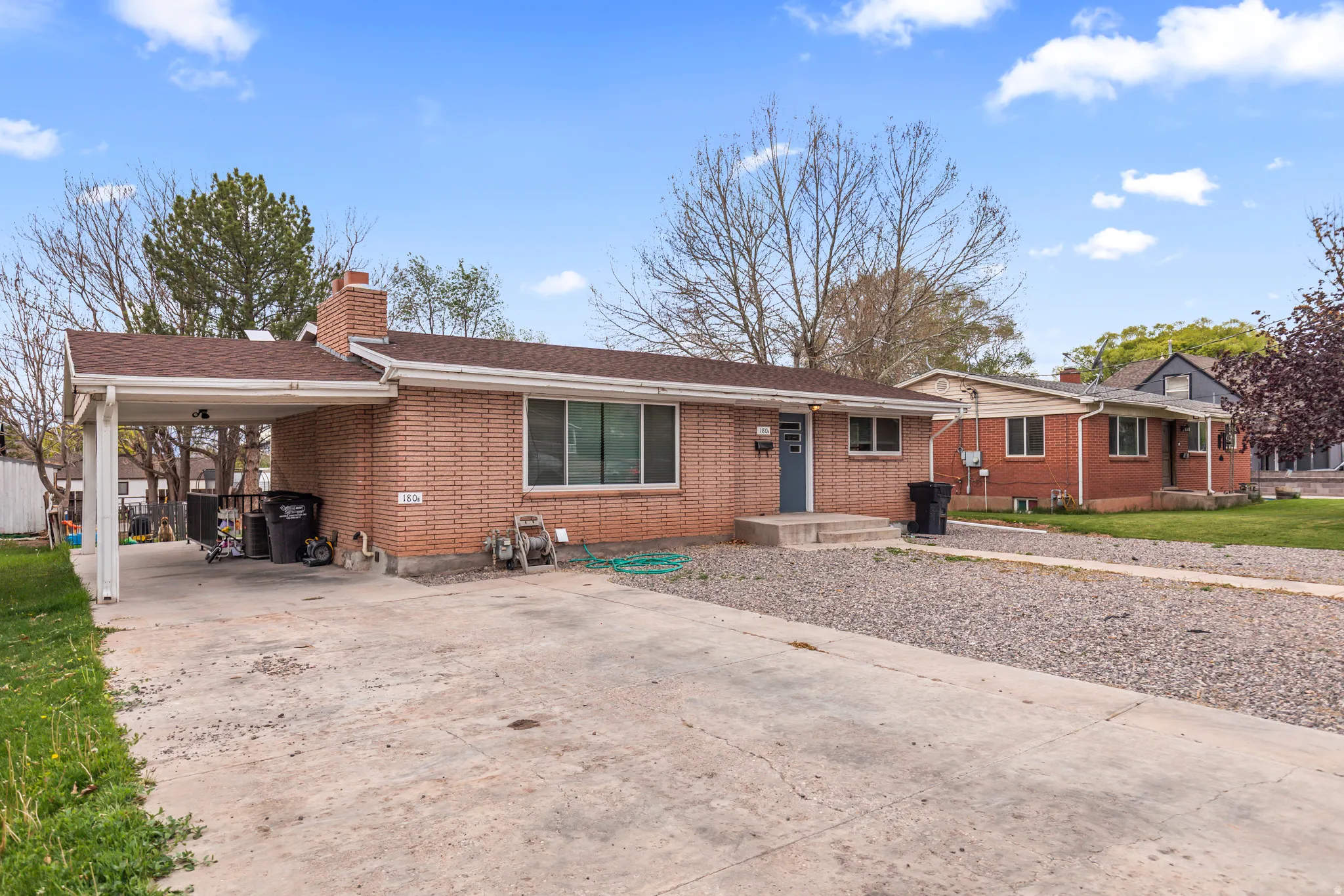 Brick single-story residence featuring a carport and an additional gravel parking area