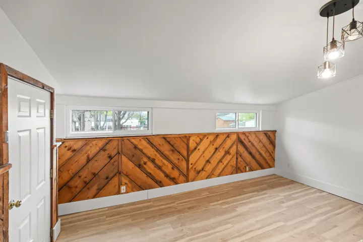 Interior space featuring wood-finish flooring, a decorative wood wall panel with a chevron pattern, and white painted walls