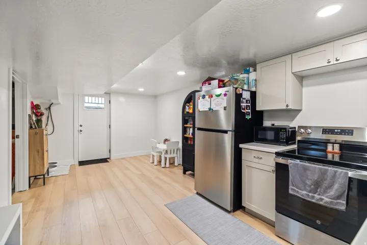Kitchen area featuring light wood-finish flooring, white walls, recessed lighting, and a white entry door with a window