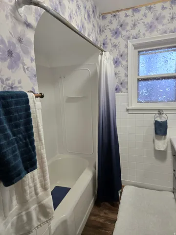 White bathtub and shower surround with a curved shower rod