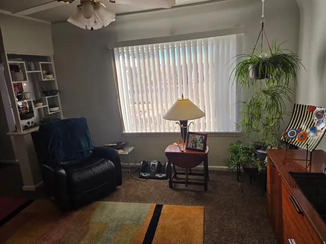Living area with a large window featuring horizontal blinds