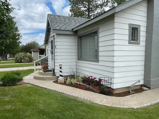 White siding exterior with a dark gray shingle roof and a concrete entry path