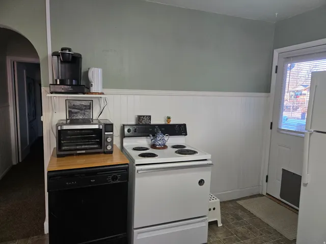 Kitchen area featuring a white electric range, black built-in dishwasher, and wood-finish countertop