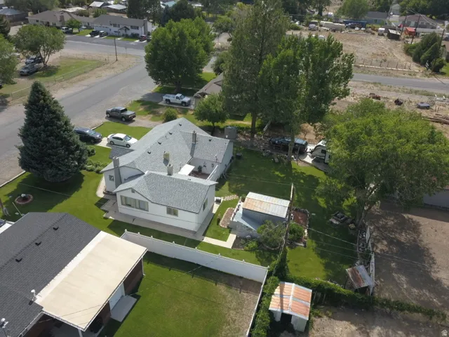 Expansive property featuring a white exterior residence with a light gray shingle roof, surrounded by mature trees and manicured lawns