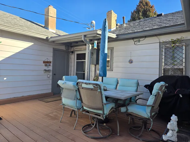 Expansive wood-finish deck with white siding exterior