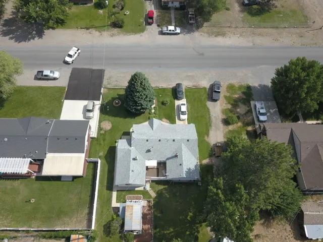 Gable roofline property featuring a front yard with mature trees and a paved driveway