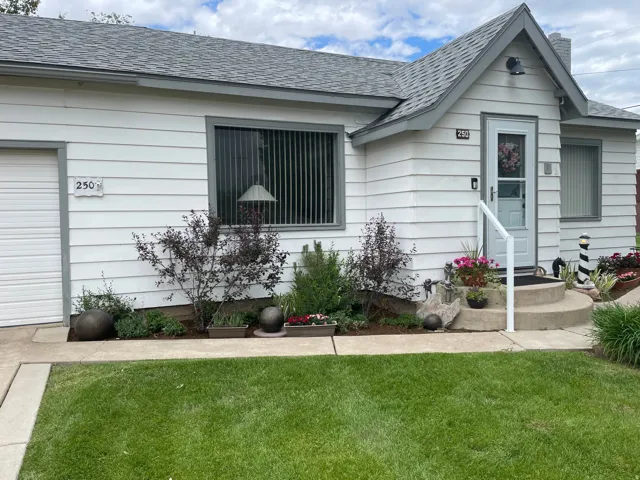 White siding exterior with a pitched shingle roof, a single-car garage, and a concrete entry porch with a white handrail