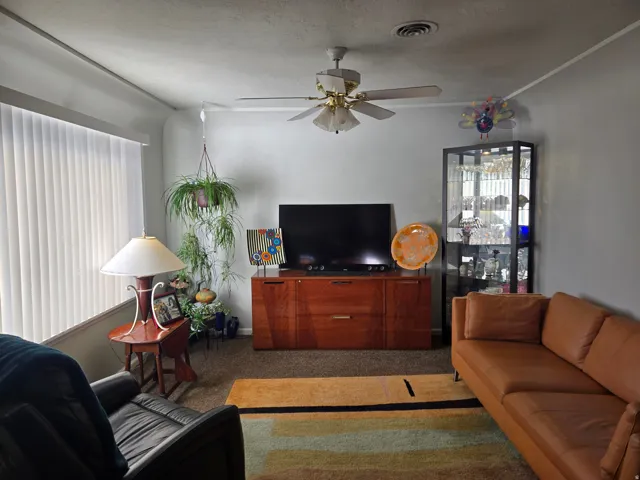 Spacious room featuring neutral wall paint, vertical blinds, and ceiling fan