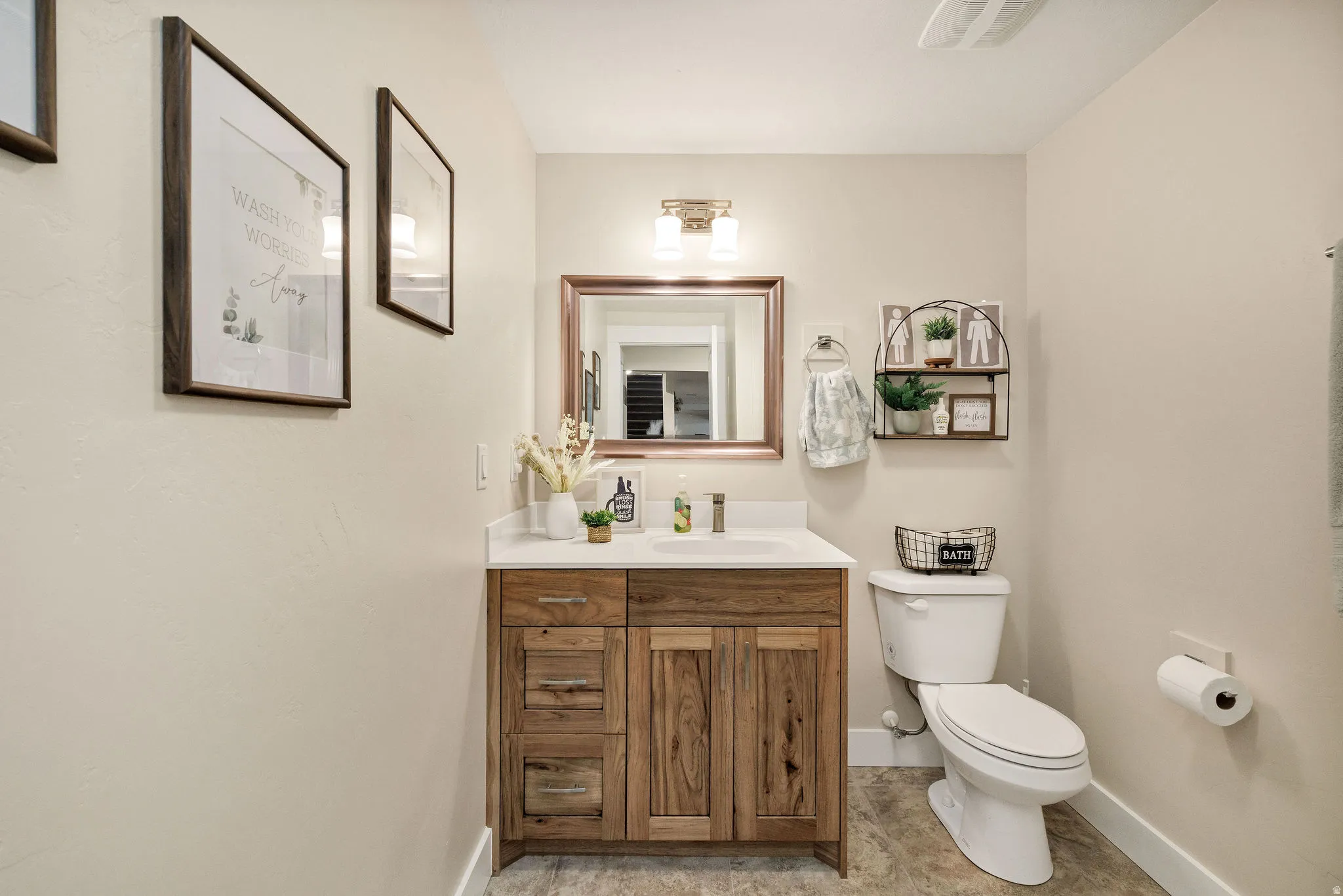 Bathroom featuring a natural wood-finish vanity with a white countertop and undermount sink, a framed mirror, and a two-light fixture