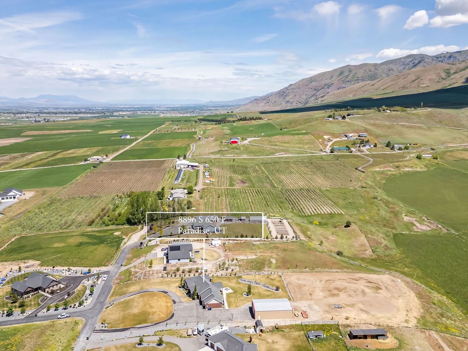 Aerial perspective of rural land featuring agricultural fields, distant mountains, and scattered residences