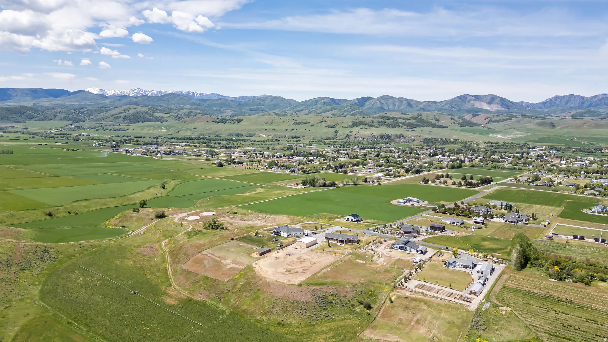 Expansive aerial view showcasing a rural landscape with distant snow-capped mountains