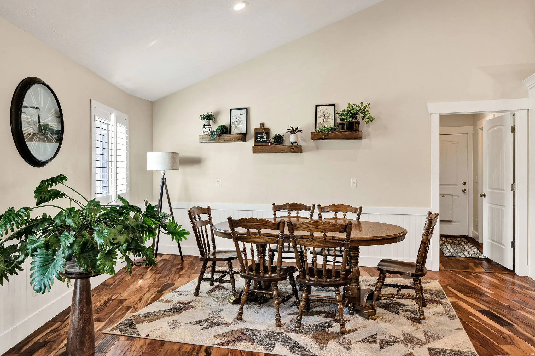 Vaulted ceiling with recessed lighting, wood-finish flooring, white plantation shutters, and wainscoting