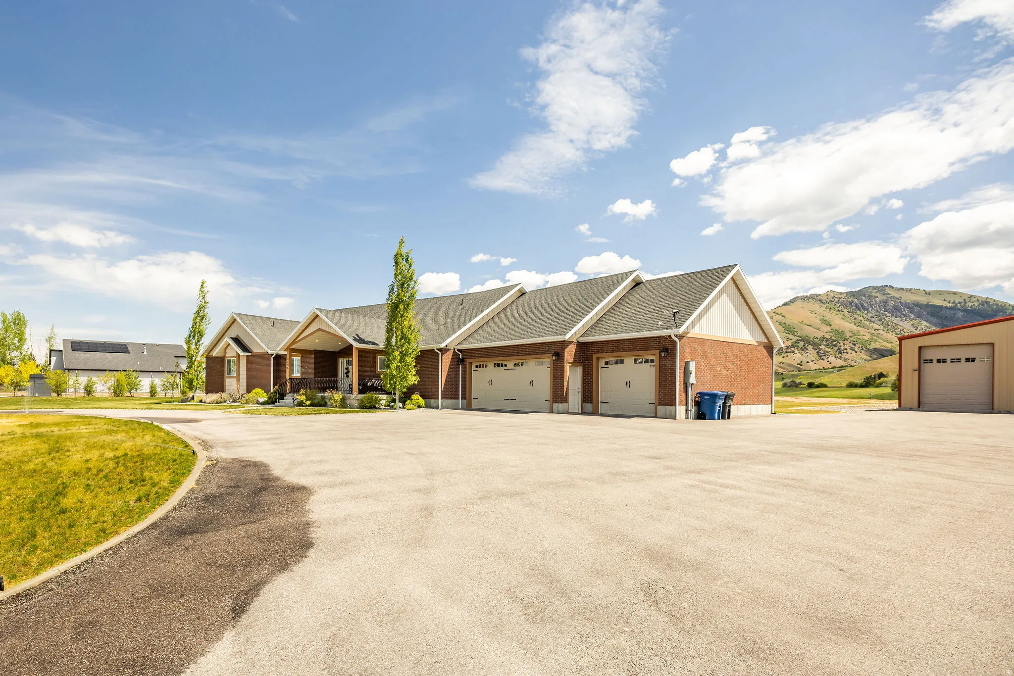 Brick exterior with a covered entryway, three-car garage, and an expansive paved driveway