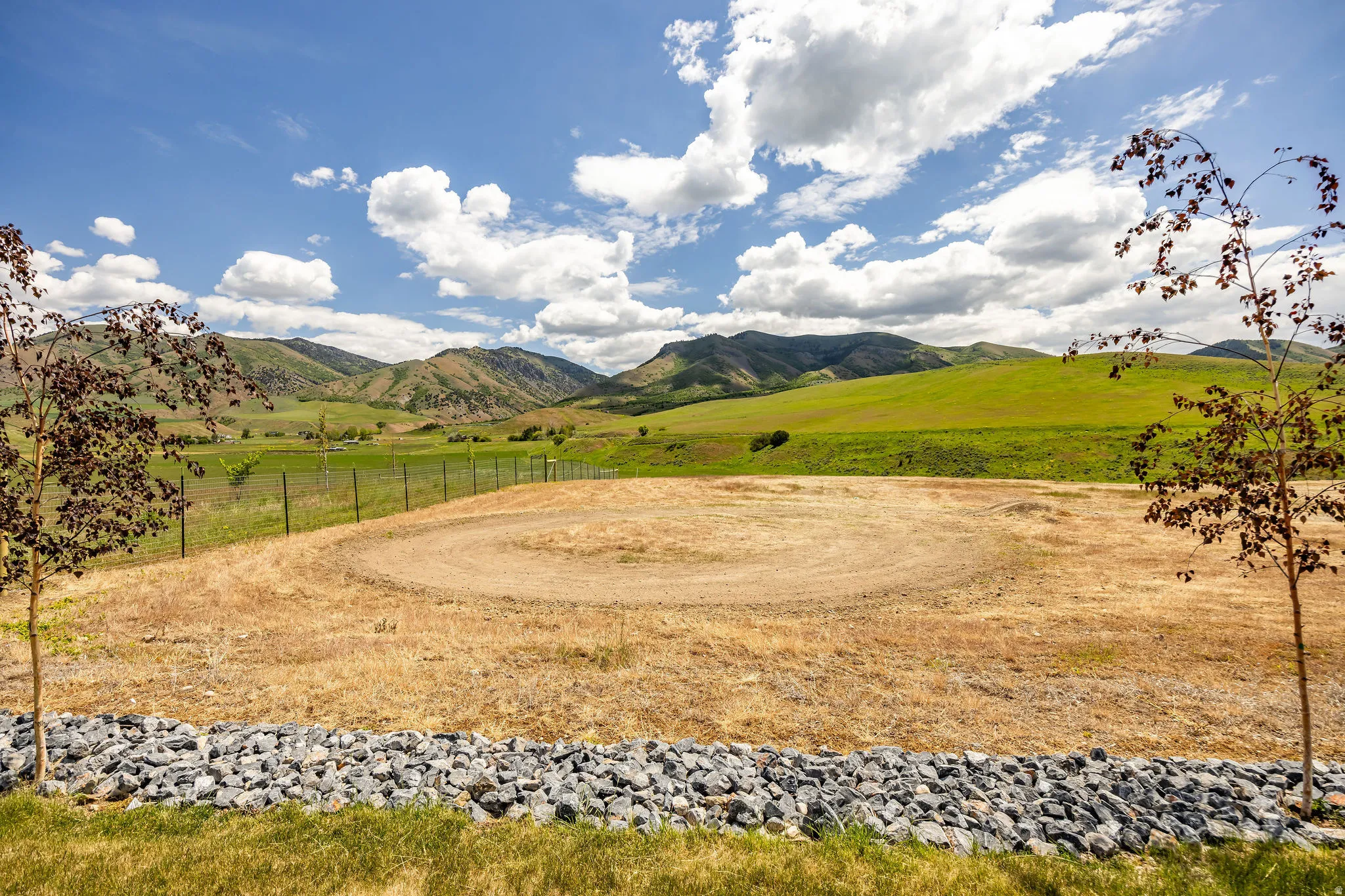 Expansive land parcel featuring a circular clearing, perimeter fencing, and distant mountain ranges