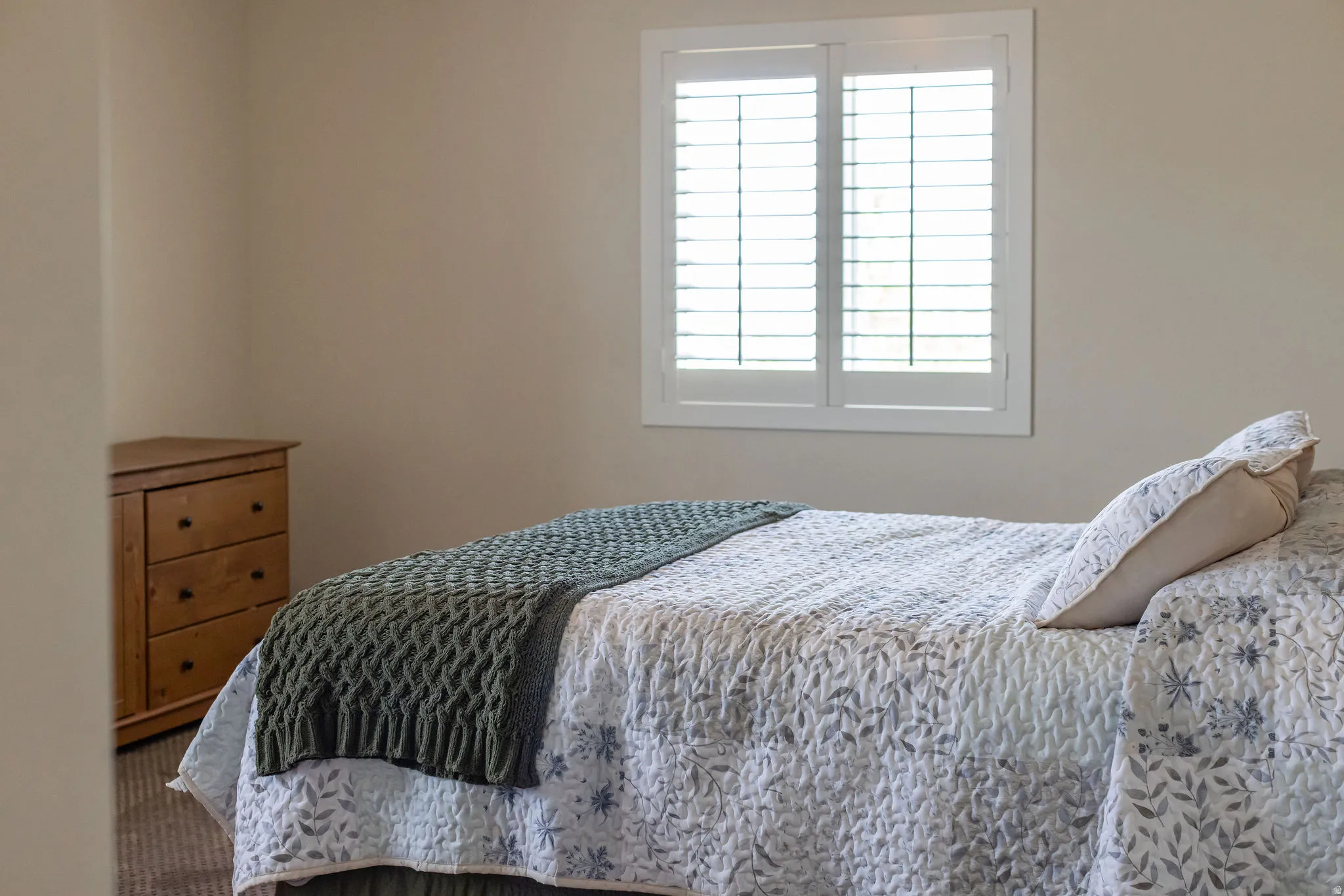Interior room featuring neutral wall finishes, a window with plantation shutters, and carpet flooring