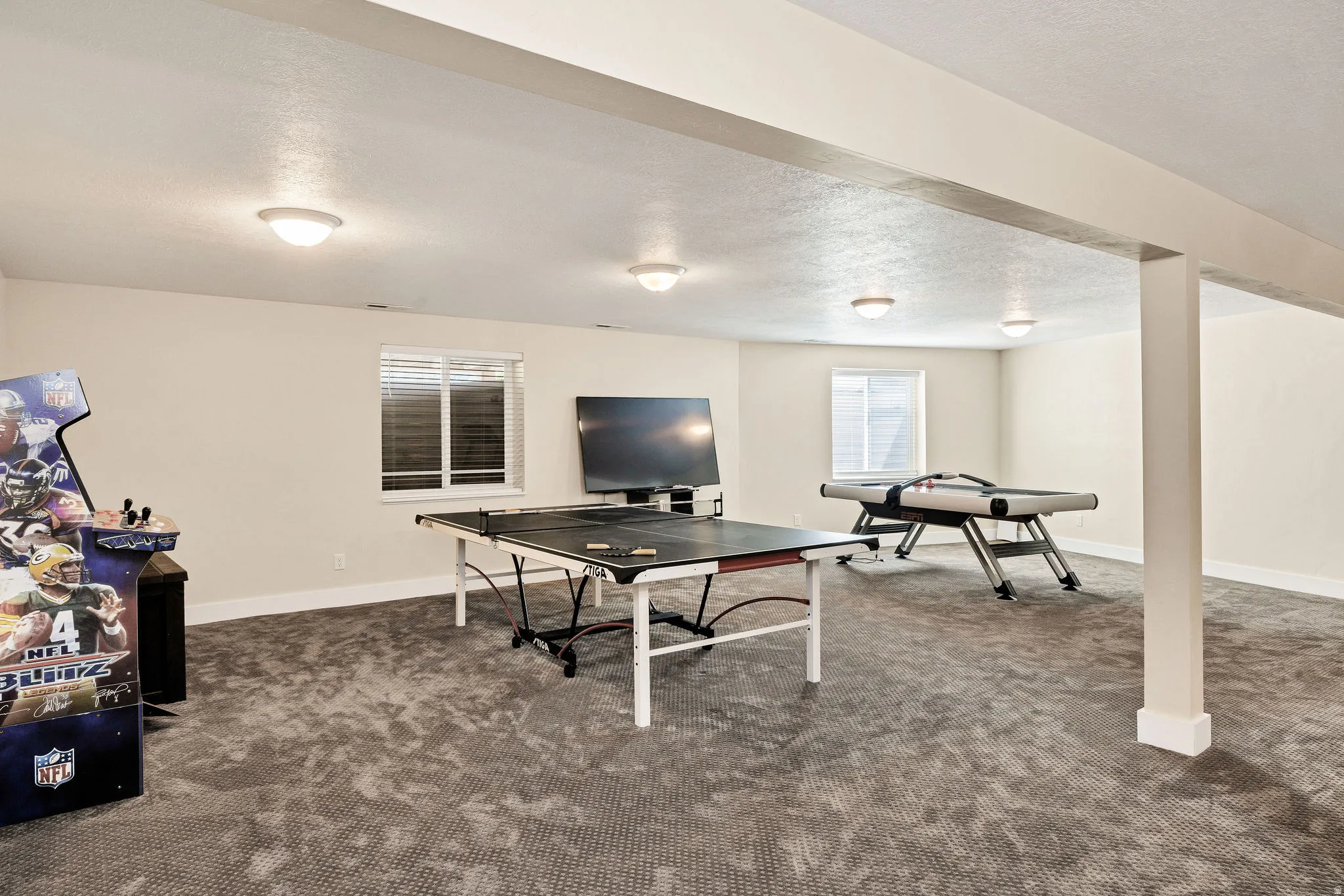 Spacious recreational room featuring recessed lighting, neutral wall tones, and plush carpeting