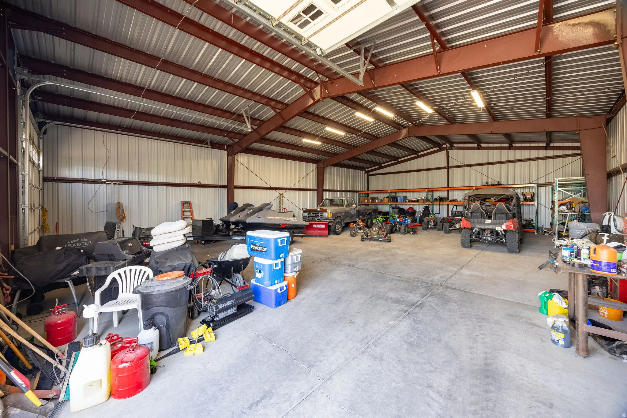 Spacious metal building with a concrete floor, exposed steel beam construction, corrugated metal walls, and overhead lighting