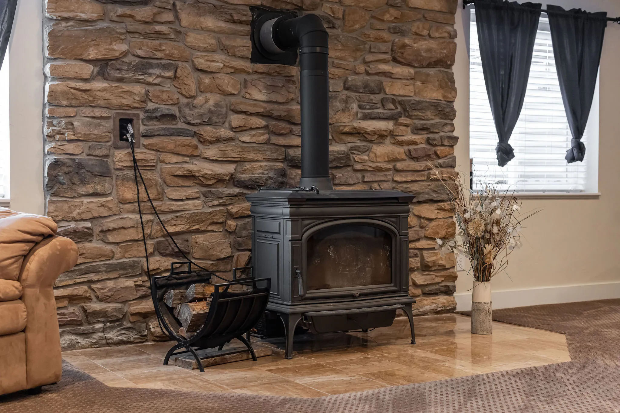 Stone accent wall featuring a black wood-burning stove