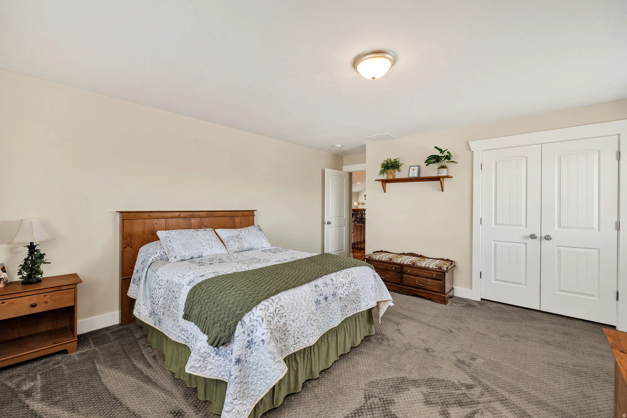Spacious bedroom featuring neutral wall tones, plush gray carpeting, white baseboards, and a semi-flush mount ceiling light