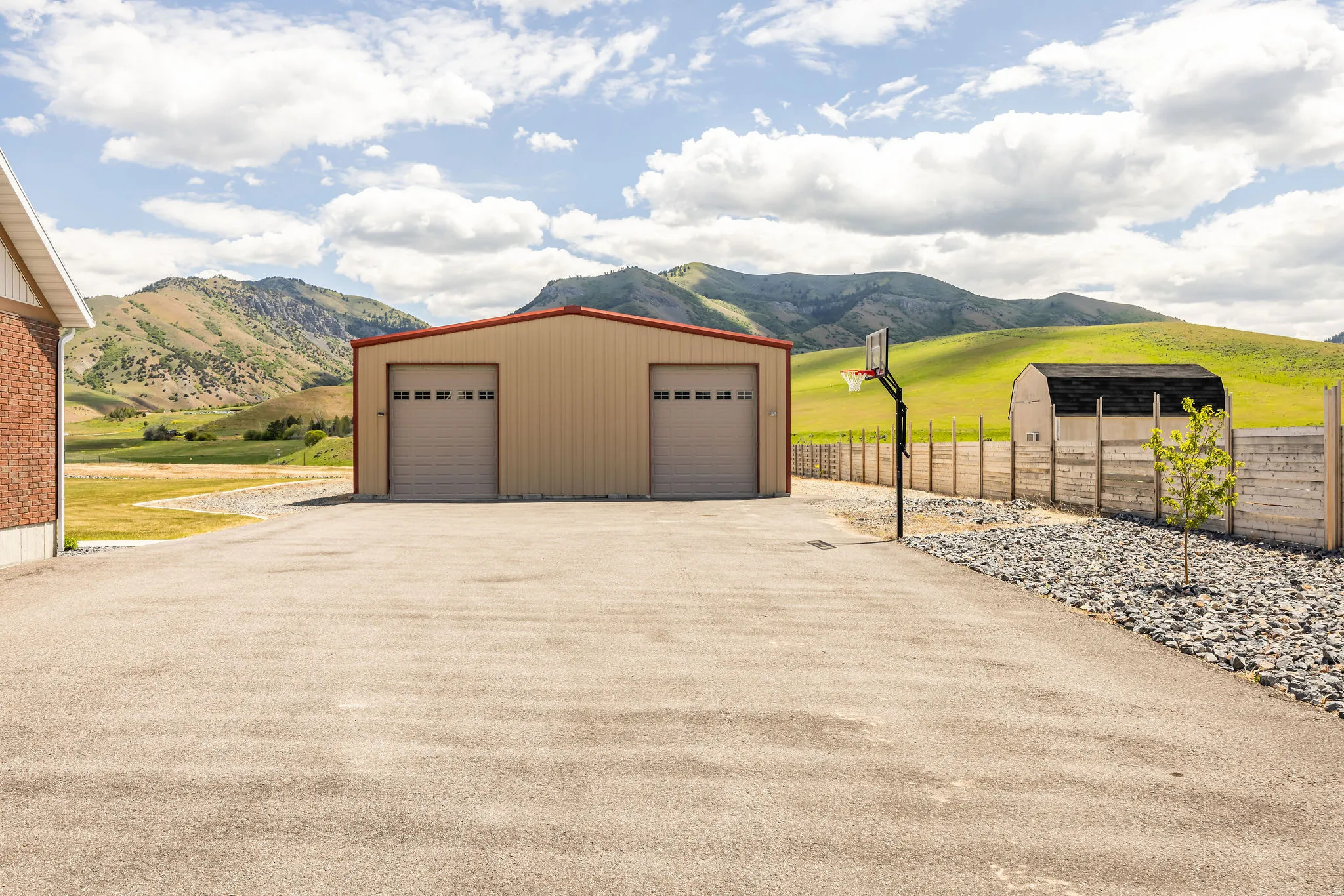 Spacious asphalt driveway fronting a large two-bay metal outbuilding with overhead doors
