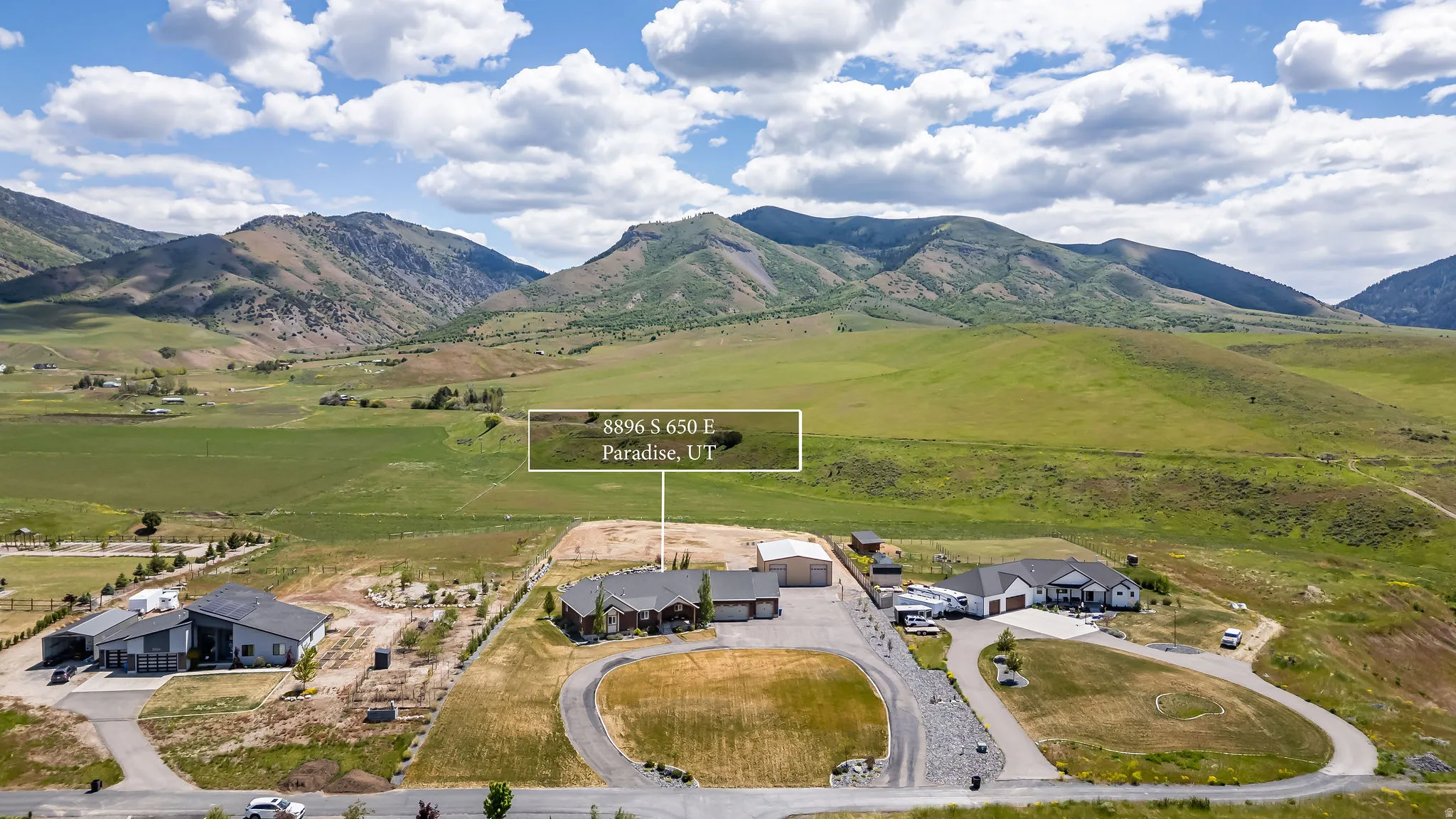 Expansive property featuring a circular driveway, a large detached garage, and substantial surrounding land