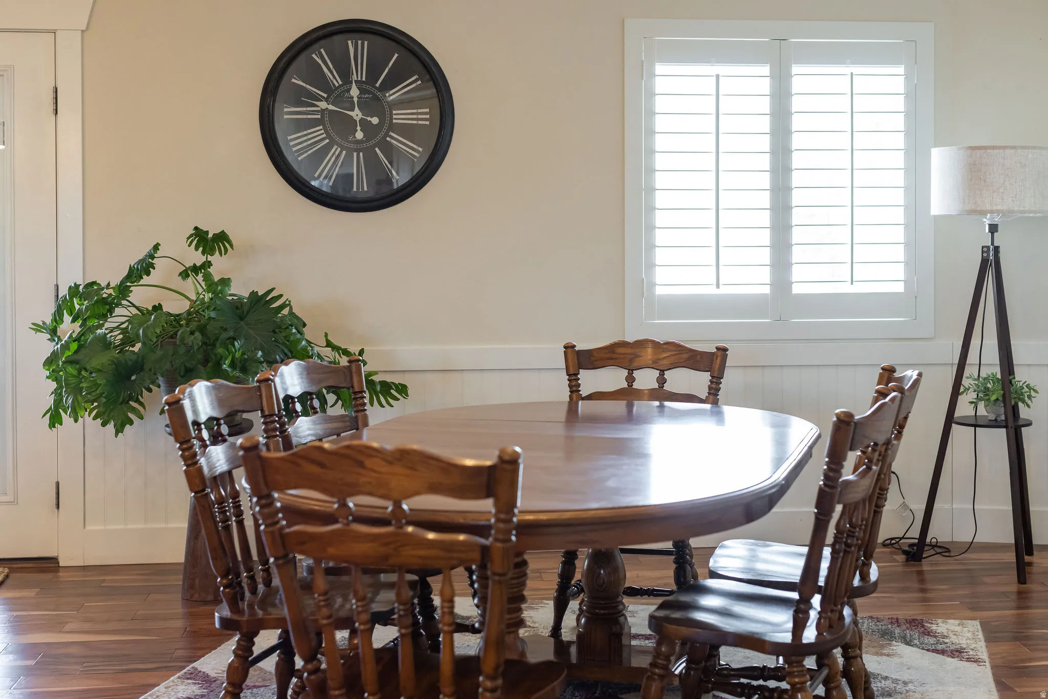 Room featuring wood-finish flooring, white plantation shutters, and wainscoting