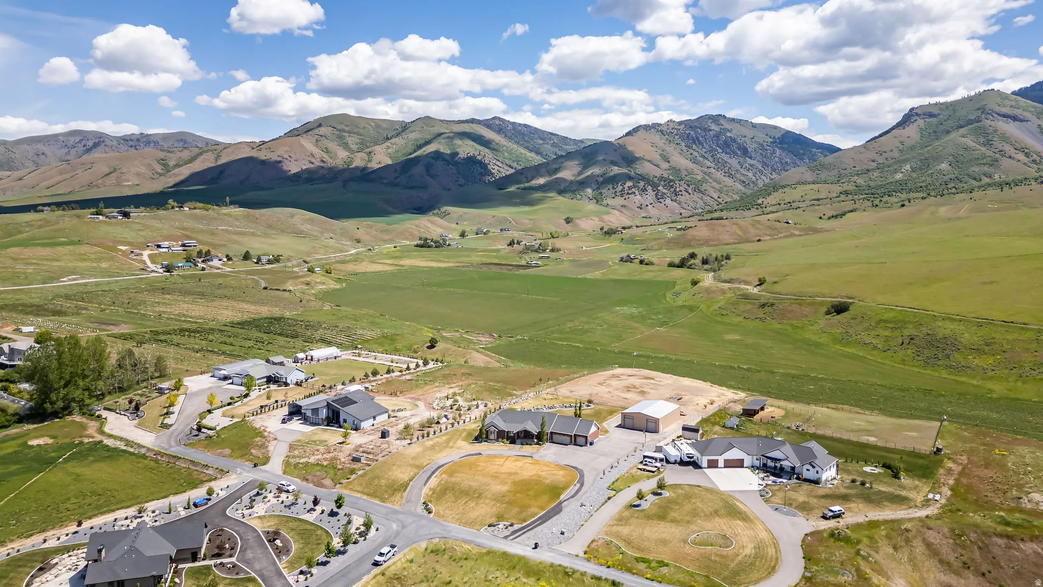 Expansive property featuring multiple single-story residences, paved driveways, and surrounding verdant terrain