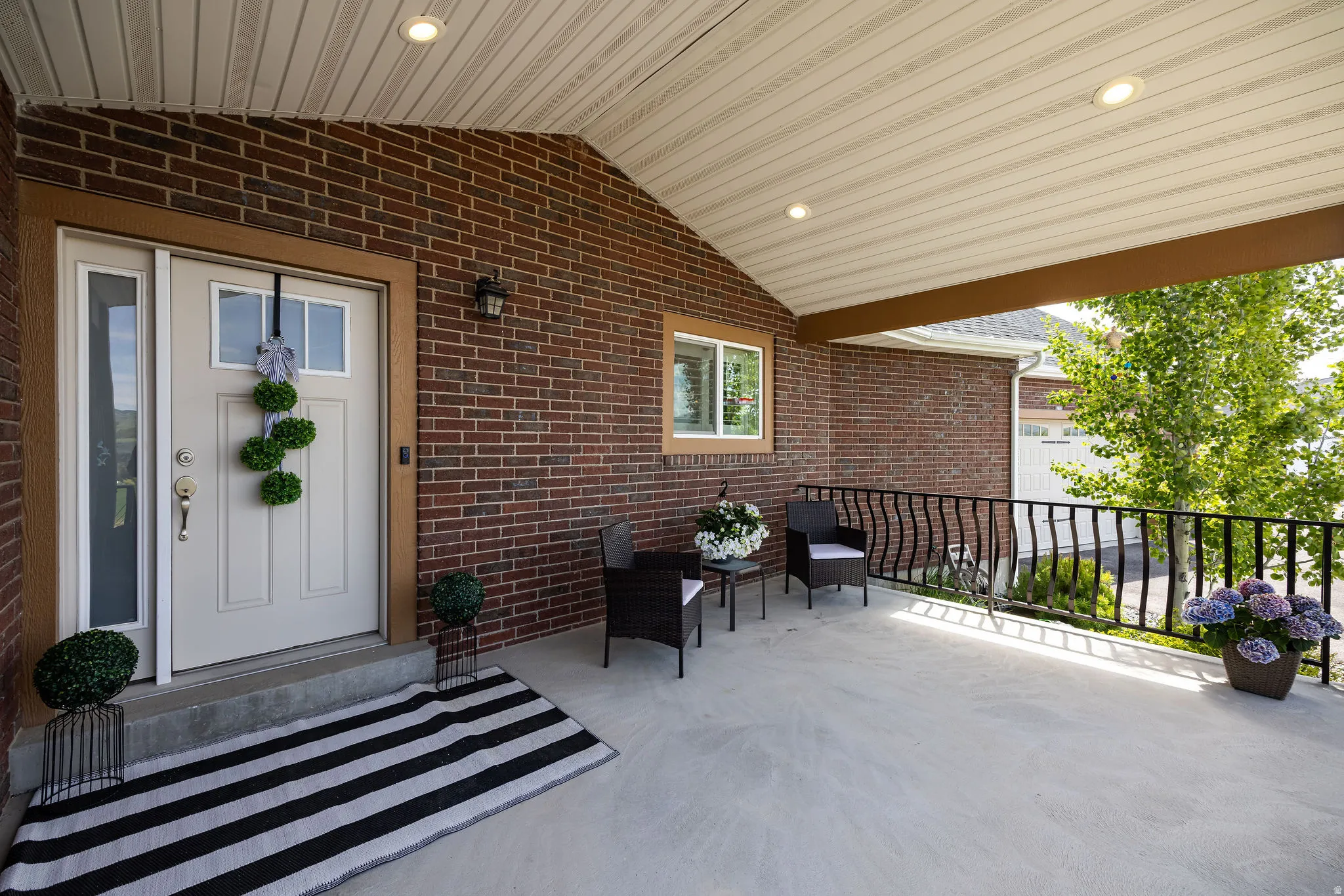 Covered front porch featuring a brick exterior and a white entry door with a sidelight