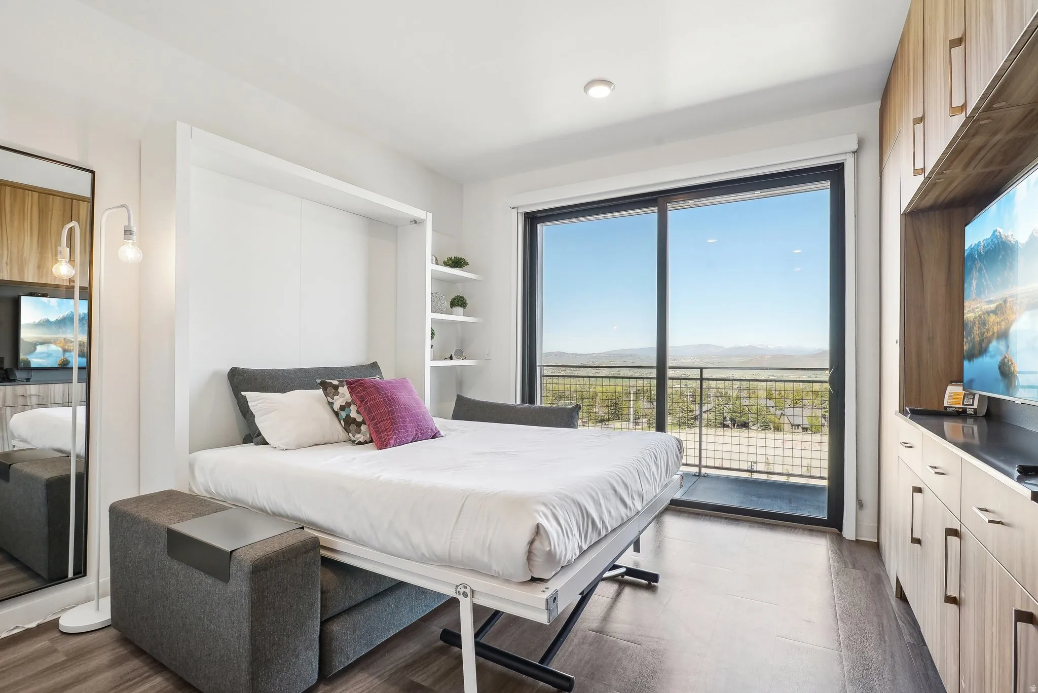 Sliding glass door opening to a balcony with metal railing, offering expansive distant landscape views