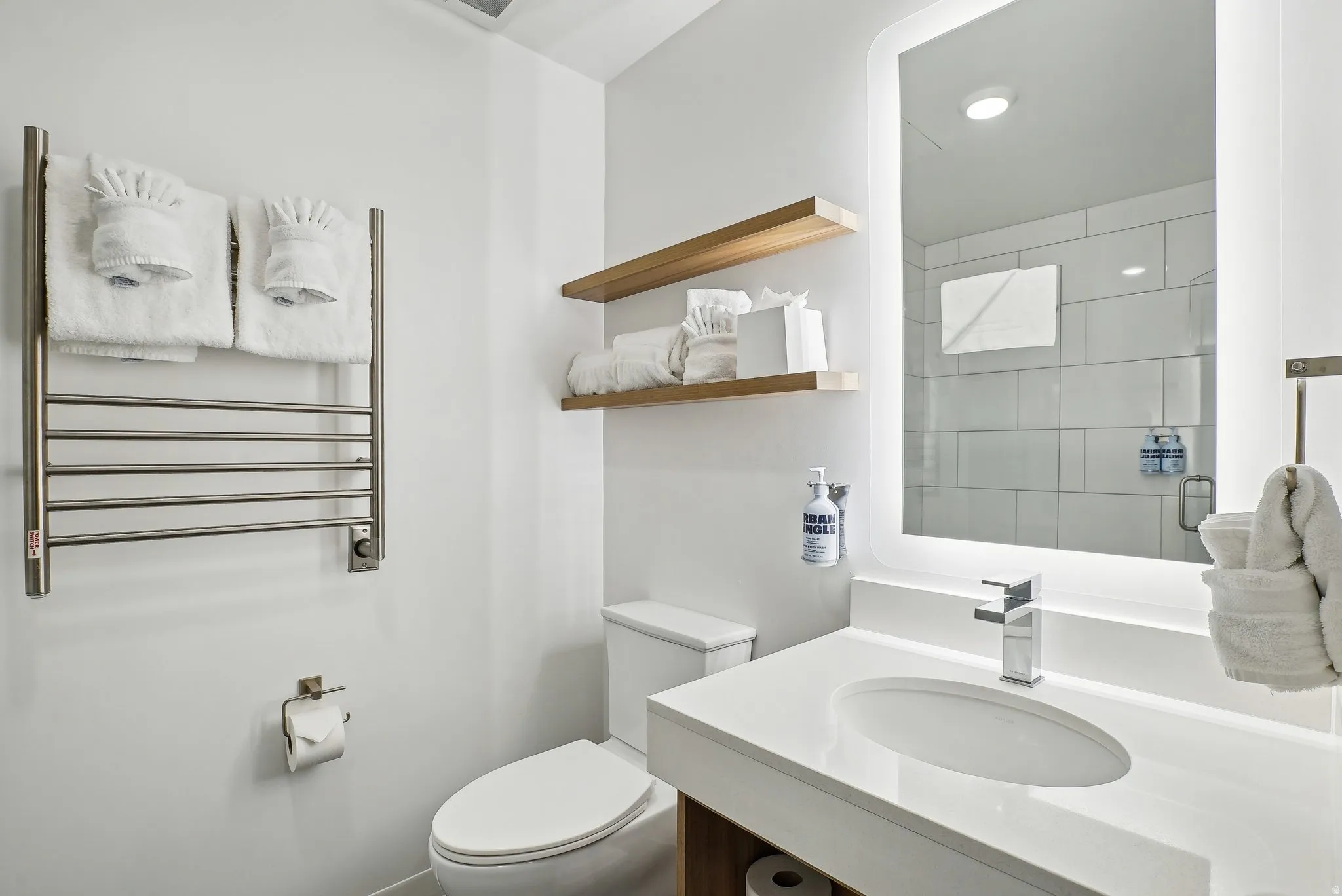 Contemporary bathroom featuring a sleek vanity with an integrated sink, illuminated mirror, and chrome faucet