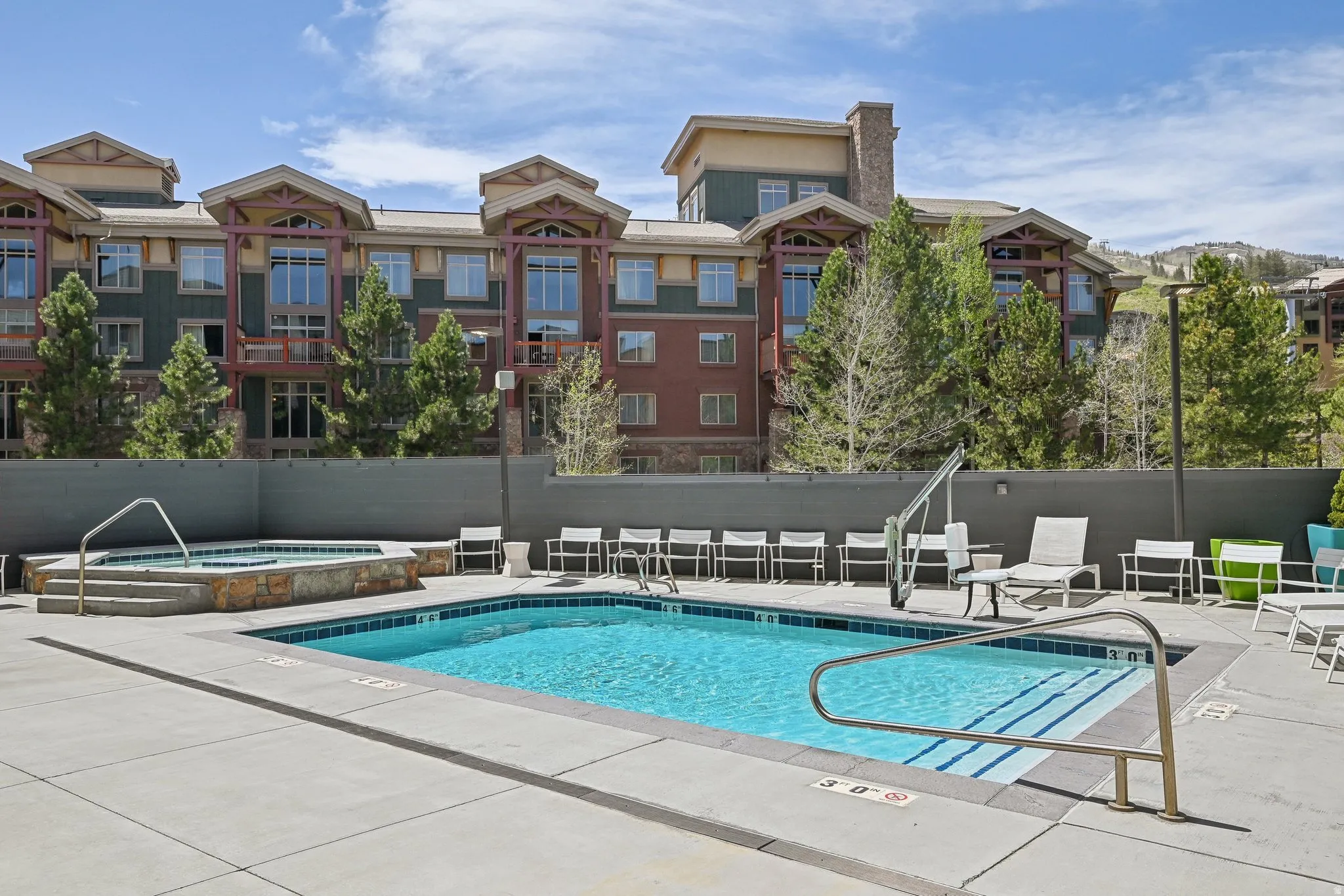 Outdoor swimming pool and hot tub area featuring a large concrete deck