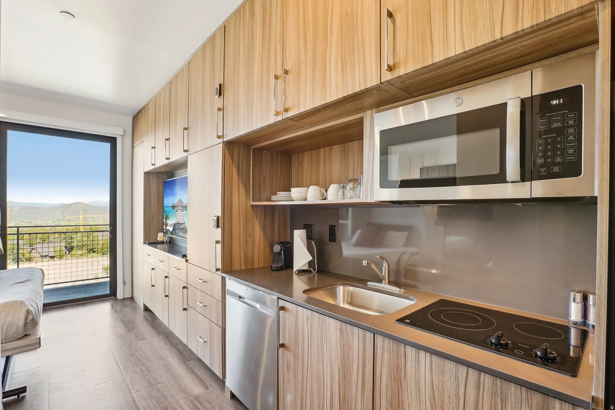 Integrated kitchenette featuring wood-finish cabinetry, stainless steel microwave, and built-in cooktop