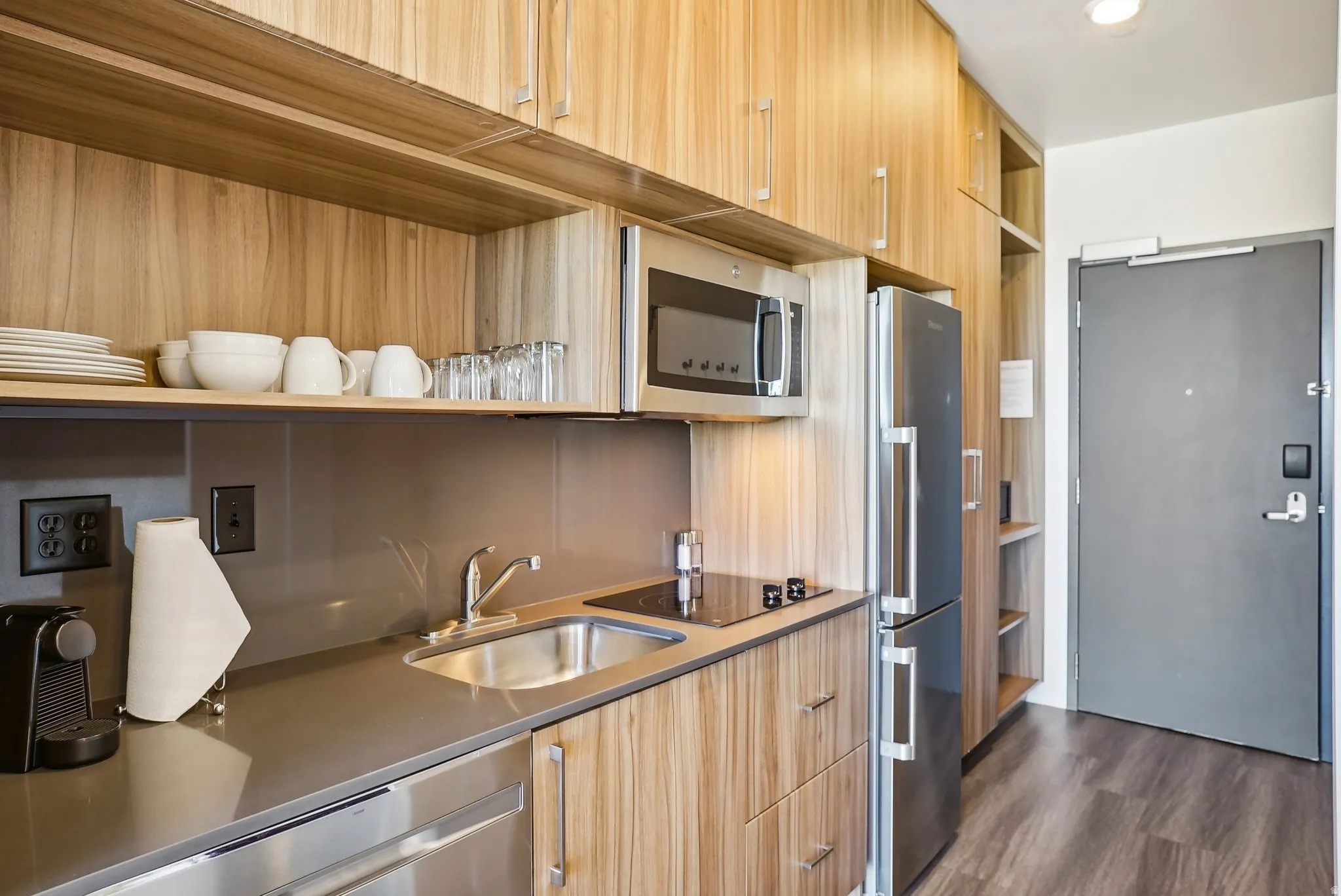 Compact kitchen area featuring wood-finish cabinetry and integrated stainless steel appliances