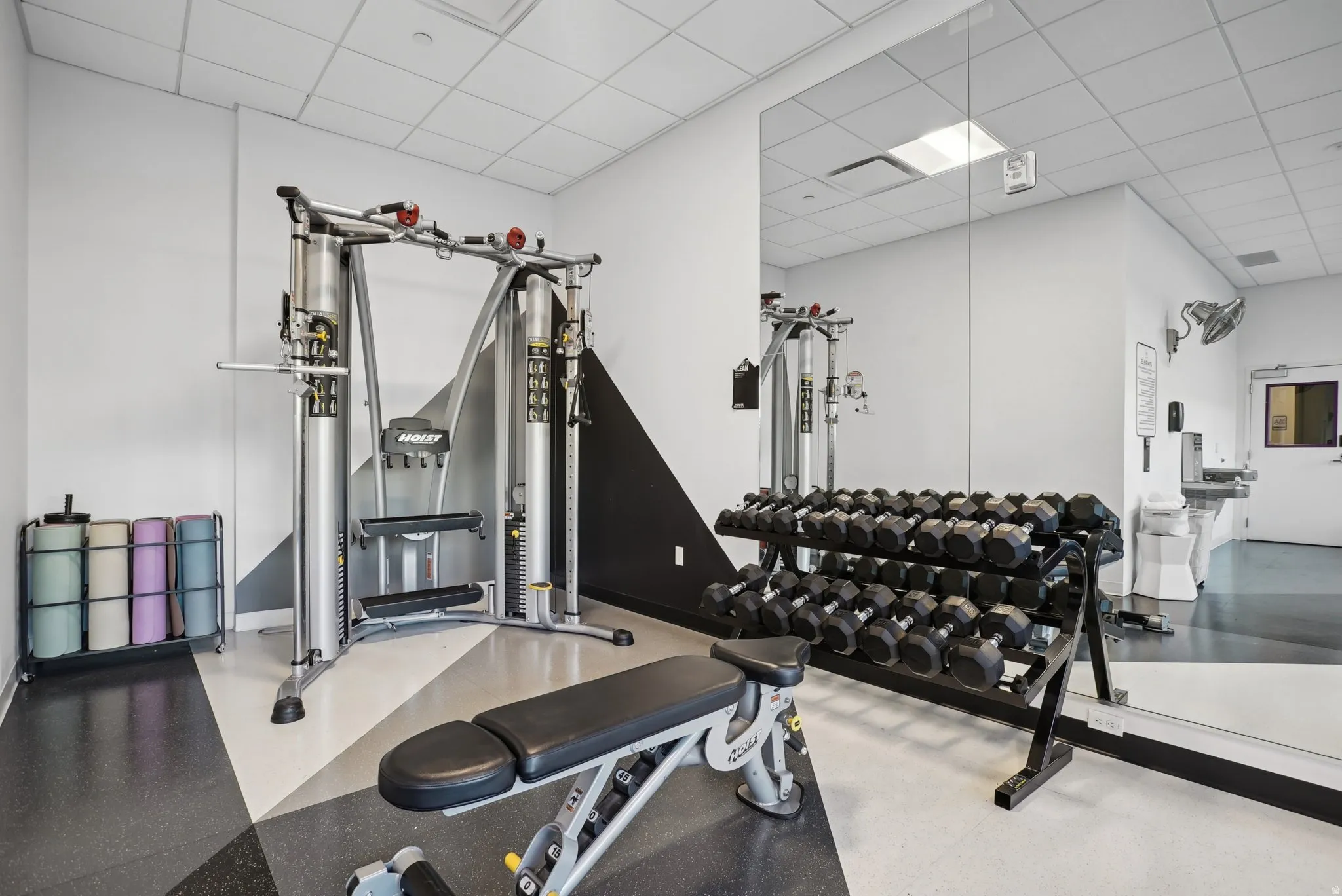 Fitness room featuring wall-mounted mirrors, a multi-station exercise machine, and a dumbbell rack