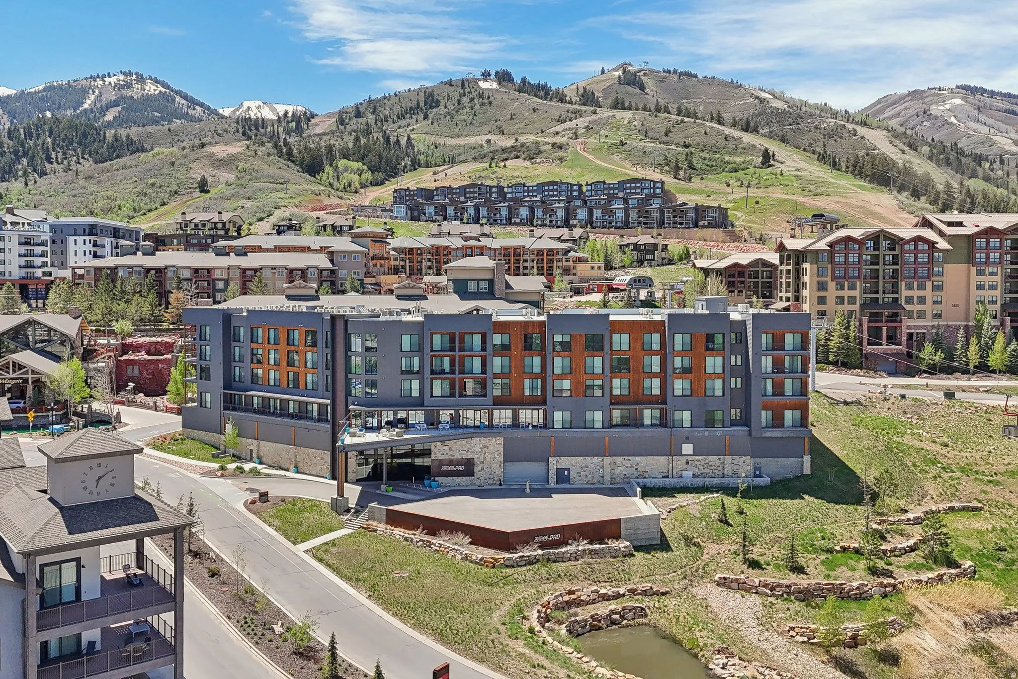 Modern multi-story building featuring a facade of gray paneling, wood-look accents, and extensive window lines