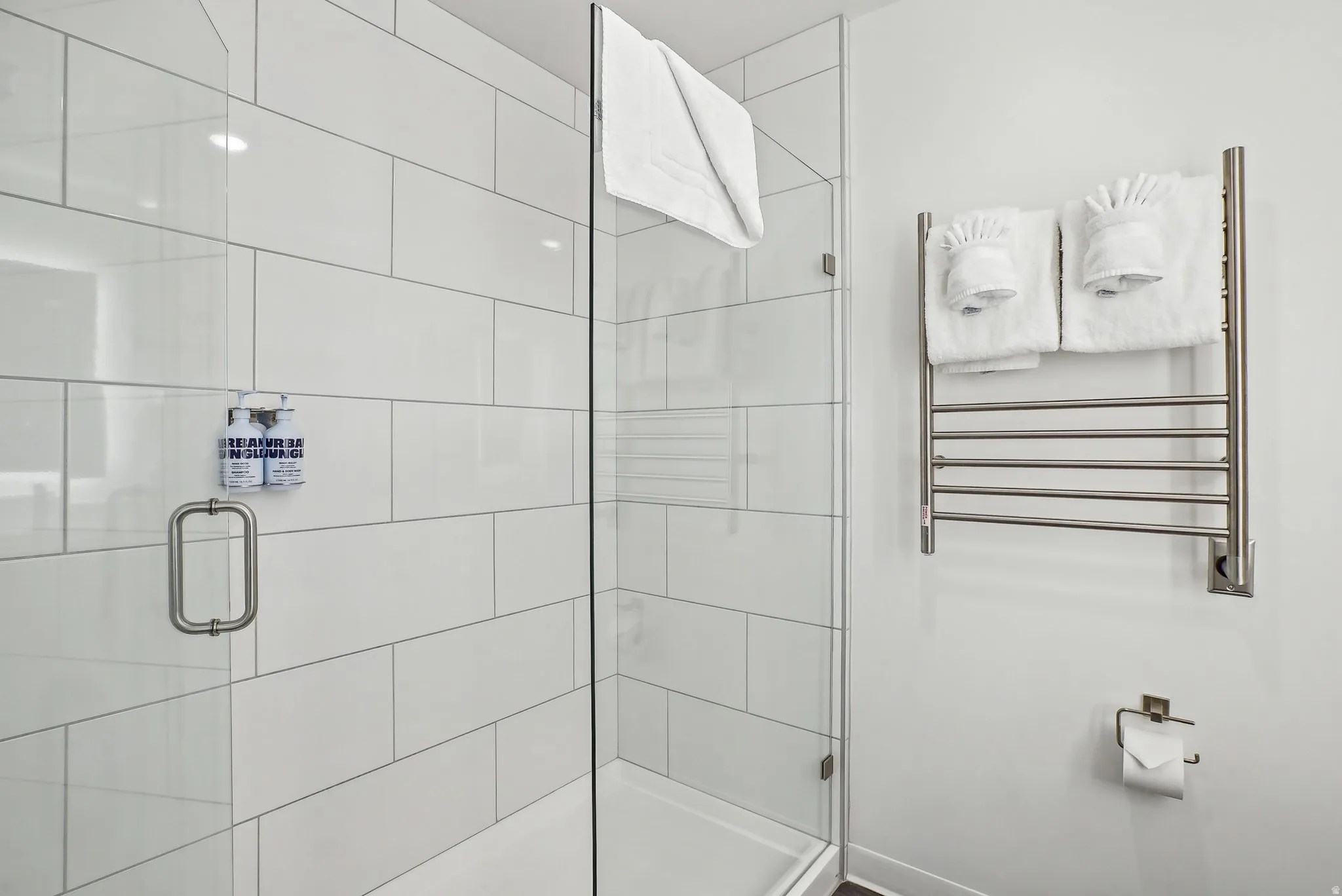Glass-enclosed shower with white subway tile surround, brushed nickel hardware, and a rainfall showerhead