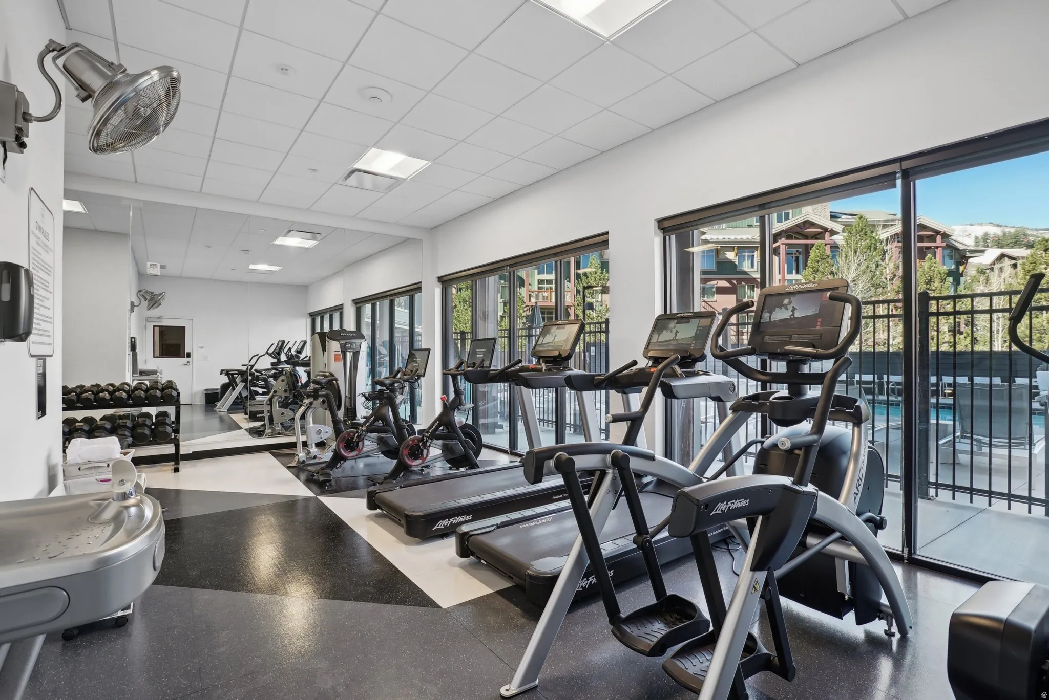 Dedicated fitness center featuring large windows, specialized flooring, recessed lighting, and a mirrored wall