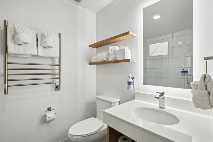 Contemporary bathroom featuring a sleek vanity with an integrated sink, illuminated mirror, and chrome faucet