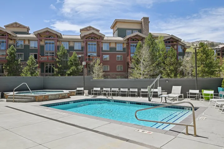 Outdoor swimming pool and hot tub area featuring a large concrete deck