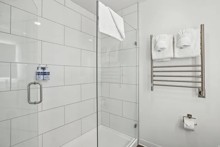 Glass-enclosed shower with white subway tile surround, brushed nickel hardware, and a rainfall showerhead