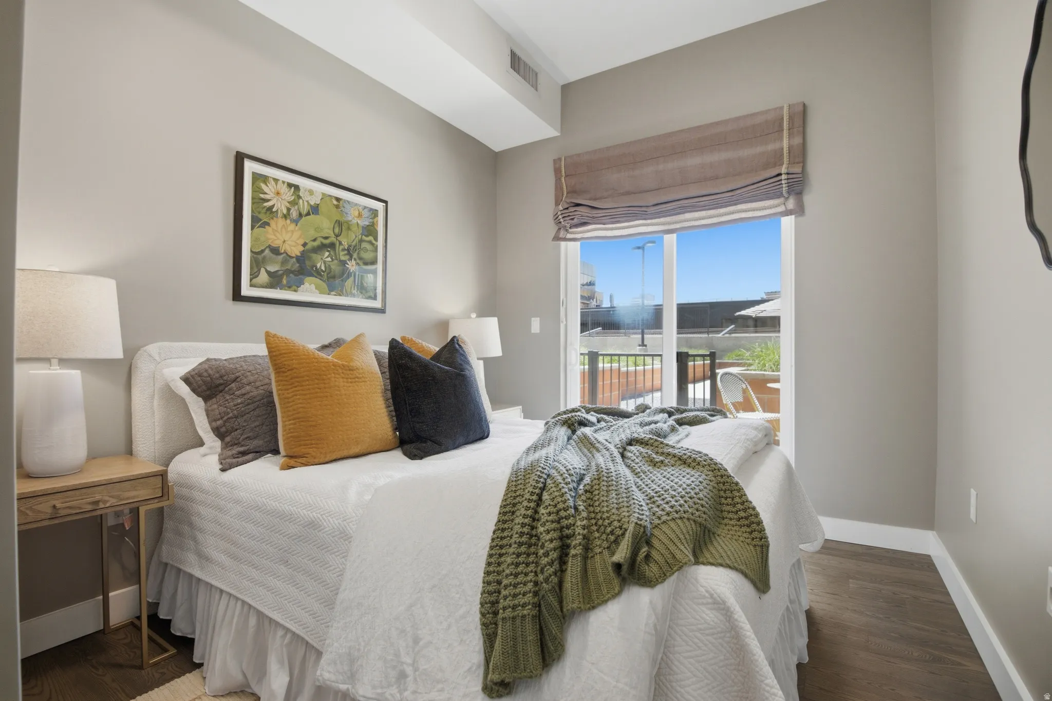 Bed space featuring a private balcony access, wood-finish flooring, and neutral wall tones