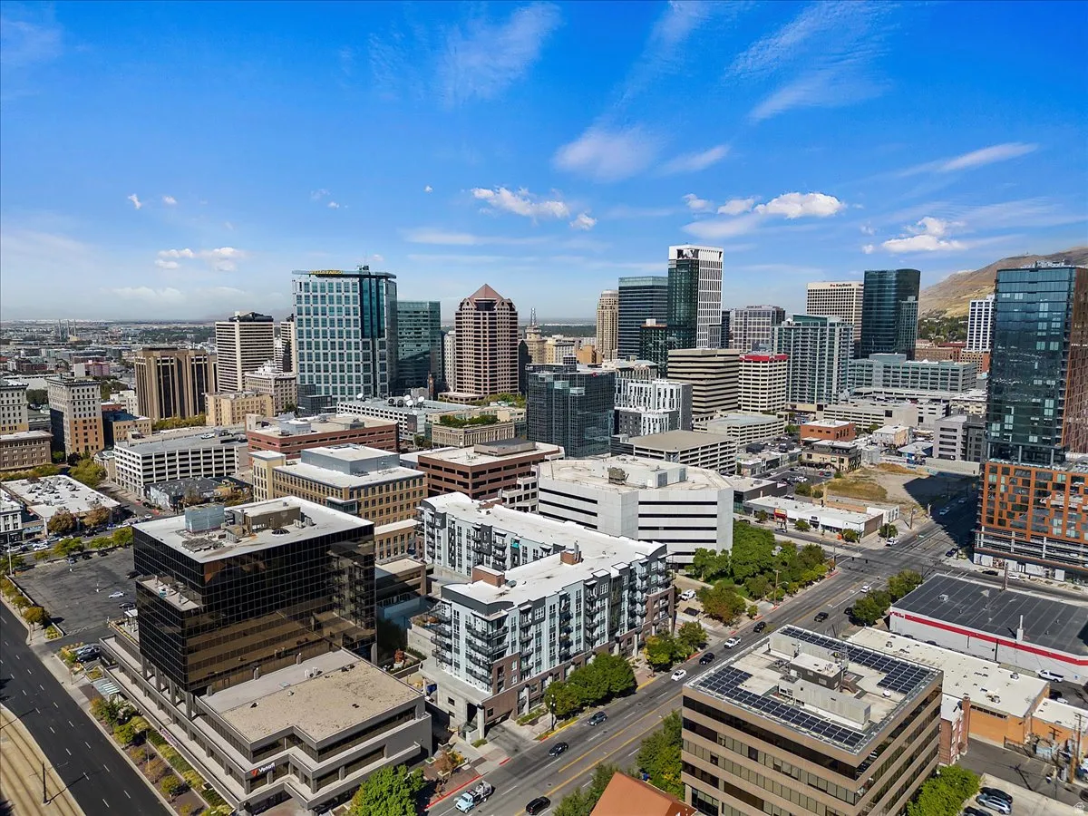 Expansive city skyline featuring various architectural styles, multiple high-rise buildings, and mountain scenery