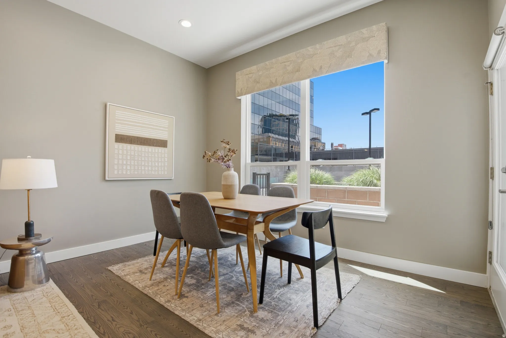 Well-lit dining area featuring wood-finish flooring, recessed lighting, and a large window with a patterned valance
