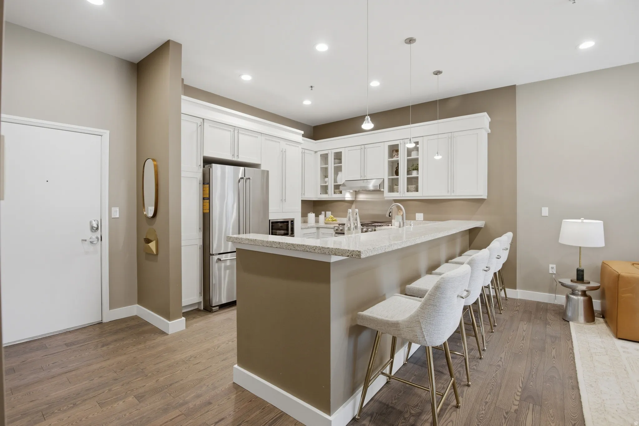 Contemporary kitchen featuring a breakfast bar with seating, white cabinetry, stainless steel appliances, and pendant lighting