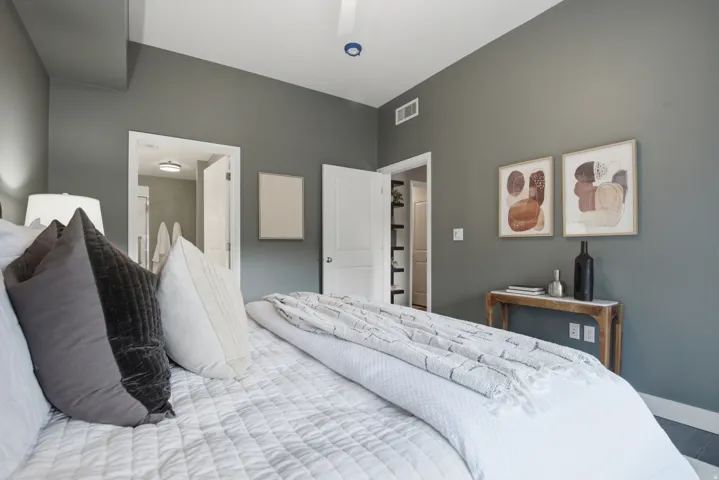 Spacious bedroom featuring neutral wall tones, a ceiling fan, and white trim