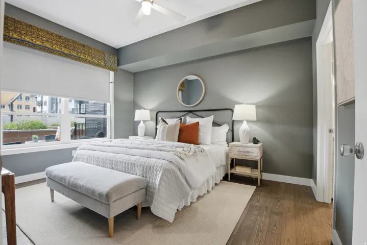 Bedroom featuring a neutral color palette, wood-finish flooring, and a large window
