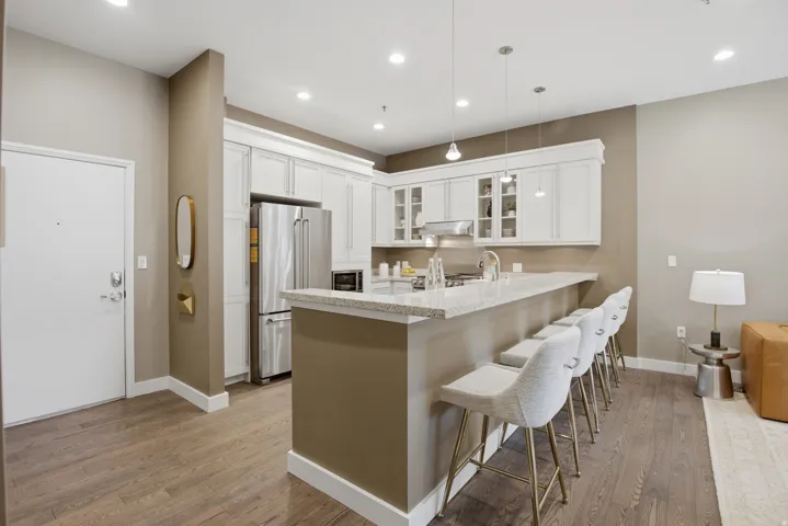 Contemporary kitchen featuring a breakfast bar with seating, white cabinetry, stainless steel appliances, and pendant lighting