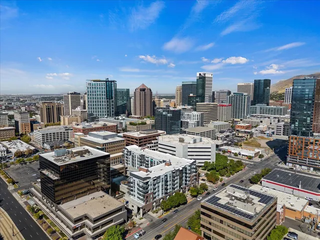 Expansive city skyline featuring various architectural styles, multiple high-rise buildings, and mountain scenery