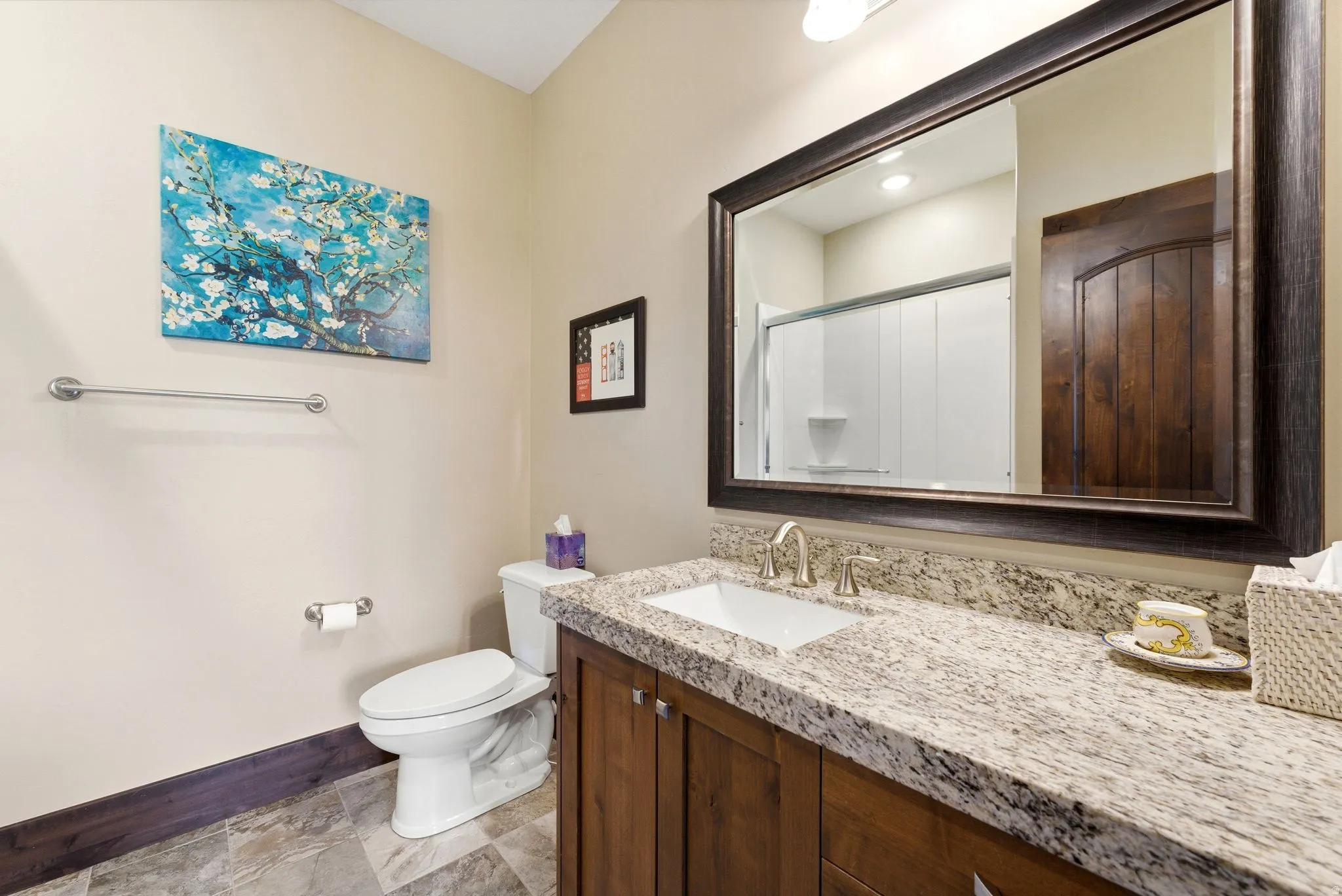 Bathroom vanity featuring a light-toned granite countertop, undermount sink with brushed nickel faucet, and wood-finish cabinetry